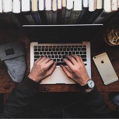 a person typing on a laptop computer surrounded by books