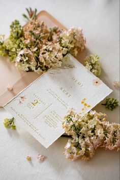 some flowers are laying next to a wedding card