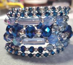 Dazzling Midnight blue fire polished and light blue glass beads. This is a wrap bracelet so it looks like you are wearing several different bracelets. This is so dazzling and beautiful. Would look great with a white t shirt and jeans or your Sunday best, it can transition from day to night.  All items from my shop come from a smoke free in home studio. Wrap bracelets are not toys. Do not give to child or leave child unattended. This product contains small parts. Bracelet is not intended for Children's use. Please inspect product for loose parts prior to use. Buyer assumes all responsibilities. NOTE: Color May Vary due to differences in color figurations on various screens and devices. I ship Items out USPS with tracking or priority mail depending on the item. Adjustable Blue Bracelets With Sparkling Stones, Blue Beaded Bracelets With Spacer Beads For Party, Handmade Blue Crystal Beaded Bracelets, Blue Crystal Beaded Bracelets With Faceted Beads, Handmade Blue Crystal Bracelet For Party, Handmade Blue Crystal Bracelet, Handmade Blue Crystal Party Bracelet, Blue Crystal Beaded Bracelets For Jewelry Making, Adjustable Blue Bling Jewelry