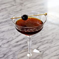 a martini glass with an olive garnish on the rim and a stick sticking out of it