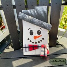 a paper snowman sitting on top of a wooden chair