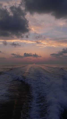 the sun is setting over the ocean with waves in front of it and some clouds