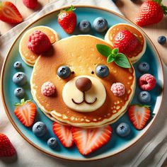 a plate topped with pancakes covered in fruit and a teddy bear face made out of pancakes