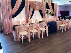 a banquet room set up with pink and blue linens, black drapes, and white chairs