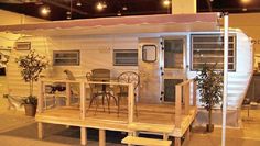 a small trailer with a table and chairs on the porch in front of an awning