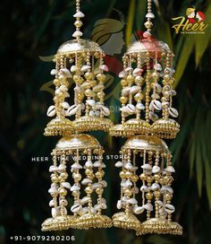 two gold and white chandelier hanging from a tree with palm trees in the background