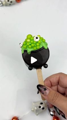 a hand holding a black and green lollipop with googly eyes on it