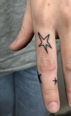 a person with a star tattoo on their ring finger and cross tattoos on the thumb