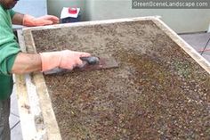 a man in green shirt sanding on top of a large sheet of dirt next to a building