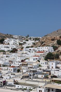 the white buildings are all over the hill side area, and there is no one in them