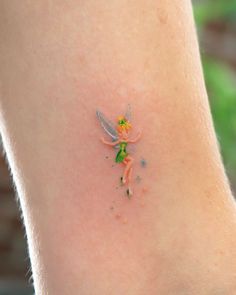 a small tattoo on the leg of a woman's ankle with tiny flowers and fairy tinkerbells all over it