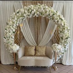 a couch sitting under a white flower covered arch