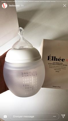 a white baby bottle sitting on top of a table next to a box and paper