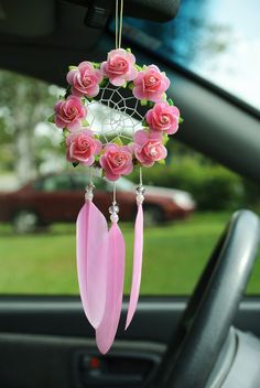 a car dashboard with pink roses and feathers hanging from it