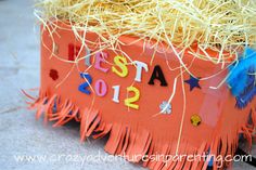 an orange box with straw and decorations on the top that says fiesta 2012 in spanish