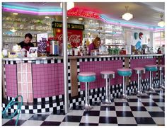 the interior of a diner with pink and black checkered flooring on the walls