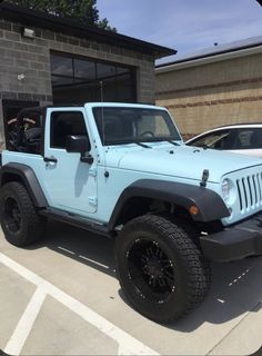 a light blue jeep parked in front of a building