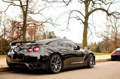 a black sports car is parked on the side of the road next to some trees