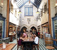 people are sitting at tables in the middle of an old brick building with exposed ceilings