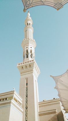 a tall white building with a clock on it's side and an open umbrella