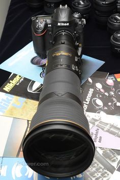 a large camera lens sitting on top of a table next to many other cameras and lenses