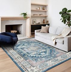 a living room with a couch, chair and rug in front of a fire place