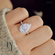 a woman's hand with a diamond ring on top of her finger and an engagement ring in the middle