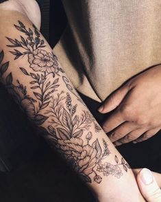 a woman's arm with flowers and leaves tattooed on the left side of her arm