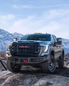 the new gmc sierra is parked on top of a rock in front of mountains