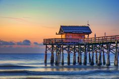 a pier with a small house on top of it in the middle of the ocean