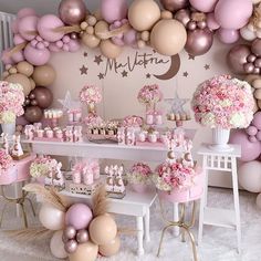 a table filled with lots of pink and gold balloons