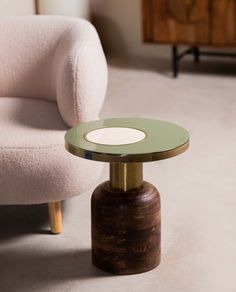 a small table with a glass top on it in front of a chair and ottoman