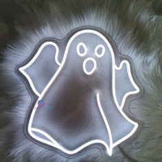 a ghost shaped neon sign sitting on top of a furry surface