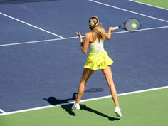 a female tennis player is swinging her racket to hit the ball on the court