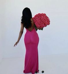 a woman in a long pink dress holding a large bouquet of roses on her shoulder