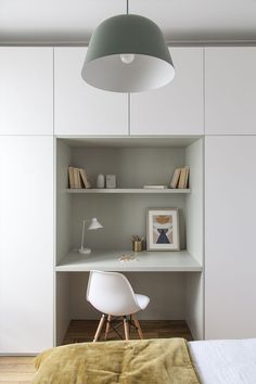 a bedroom with a bed, desk and shelves in the wall next to each other