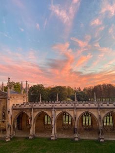 the sun is setting over an old building with arches and pillars in front of it