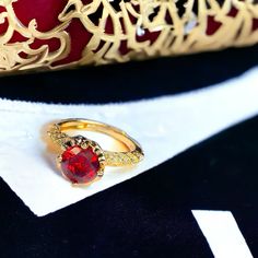 a red ring sitting on top of a piece of paper next to a gold object