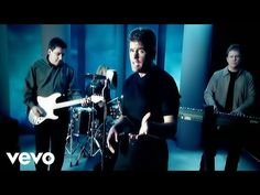 three men standing in front of microphones and guitars