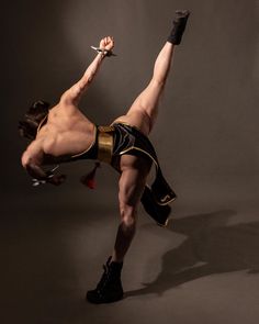 a shirtless man in black and gold shorts is doing a trick with a pair of scissors