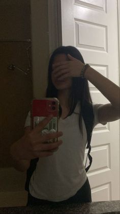 a woman taking a selfie in front of a mirror with her hand on her face