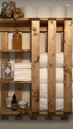 a wooden shelf filled with lots of white towels and other bathroom items on top of it