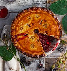 a pie on a table with berries and wine