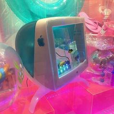 an apple computer sitting on top of a pink table next to other toys and decorations