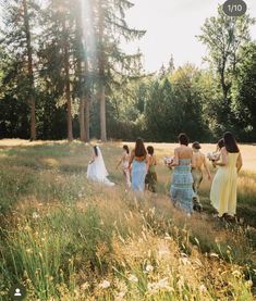 a group of women in dresses walking through a field