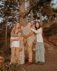 a group of people standing next to each other in front of a tree on a dirt road