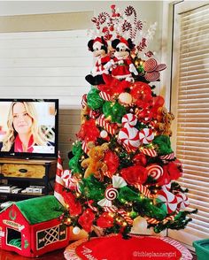 a christmas tree decorated with candy canes and mickey mouse decorations in front of a television