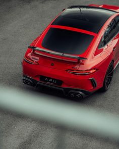 the rear end of a red sports car driving on a race track, viewed from above