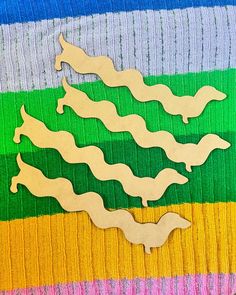 three wooden cut outs sitting on top of a colorful blanket with different colors and shapes