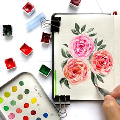 someone is painting flowers with watercolors on paper